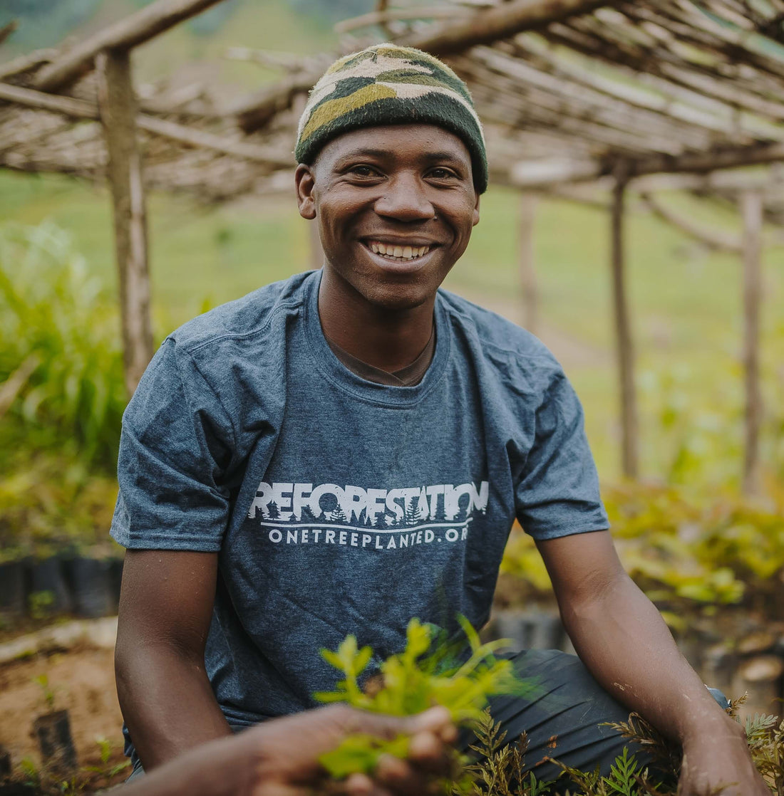 Un homme souriant et plantant des arbres